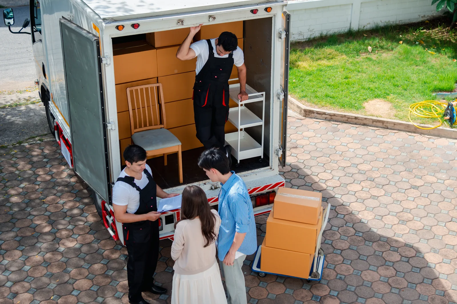 A delivery crew going through paperwork with two customers at the open back of a box truck.