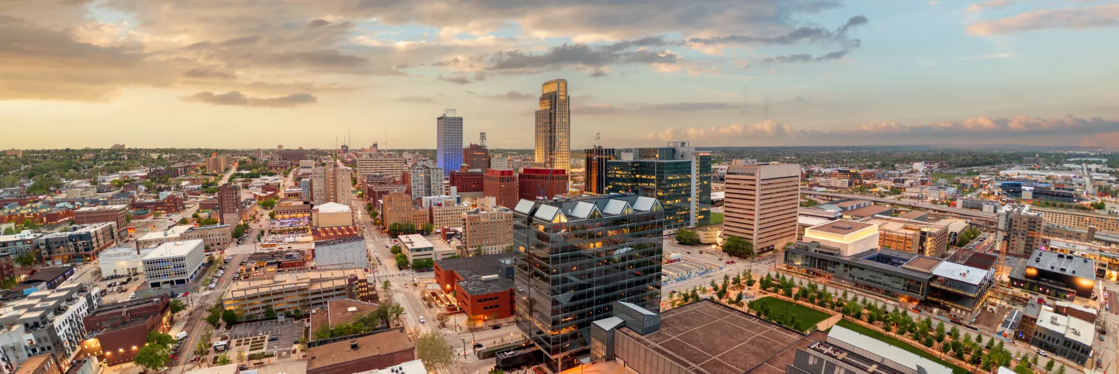 An aerial panorama of downtown Omaha at sunset, the street grid running out toward the horizon.